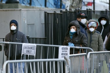 People wait in line to be tested for coronavirus disease (COVID-19) while wearing protective gear, outside Elmhurst Hospital Center in the Queens borough of New York