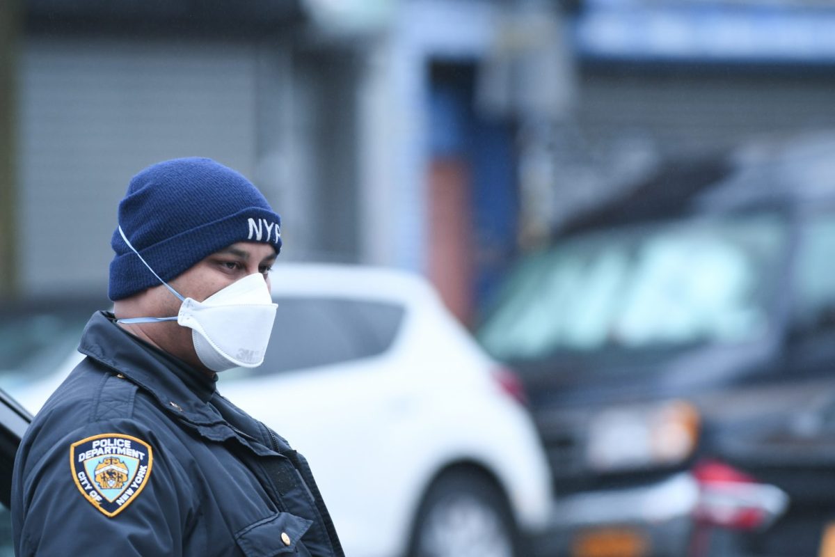 A cop from the 67th Precinct protects himself against coronavirus by wearing a mask at the scene of a shooting on East 96th Street and Rutland Road in East Flatbush, Brooklyn, on Sunday, March 29th.