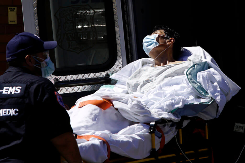 A paramedic wheels a patient into Elmhurst Hospital during outbreak of coronavirus disease (COVID-19) in New York
