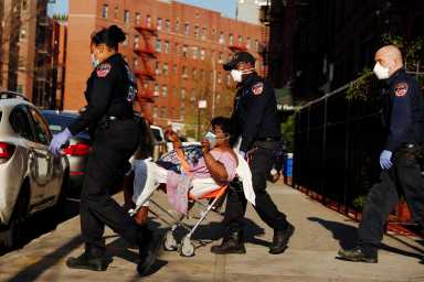 A New York City Fire Department (FDNY) Emergency Medical Technician (EMT) wearing personal protective equipment assist a woman who was having difficulty breathing during ongoing outbreak of the coronavirus disease (COVID19) in New York