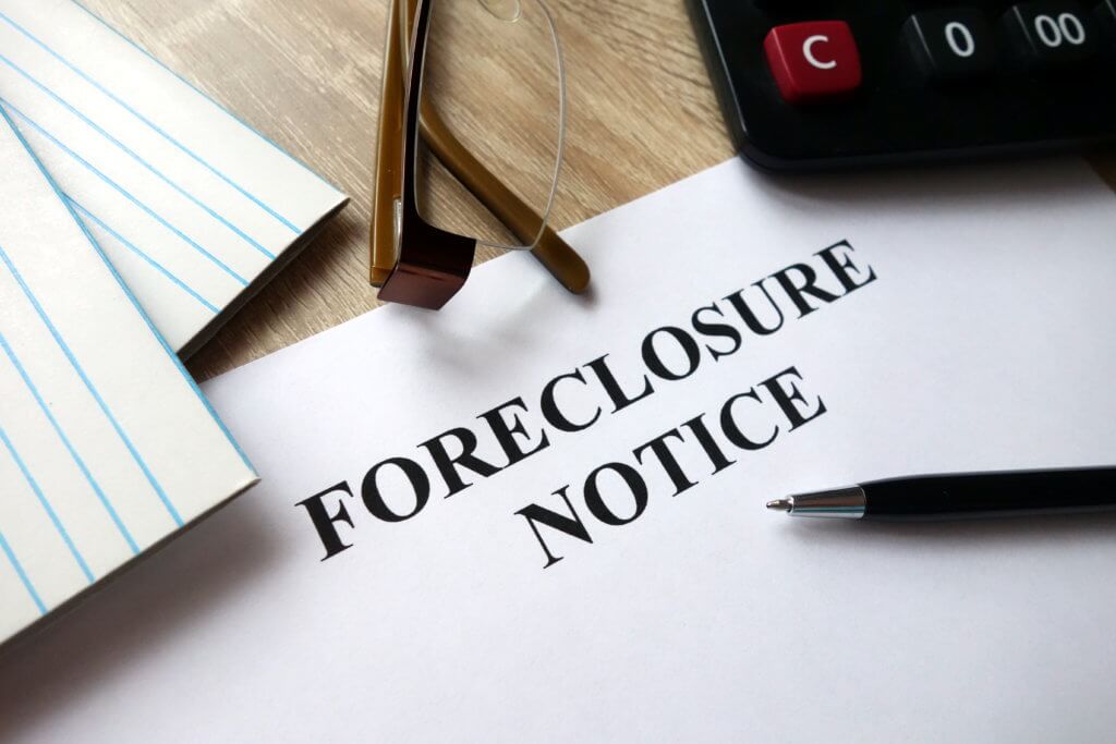 Foreclosure notice with pen, calculator and glasses in office