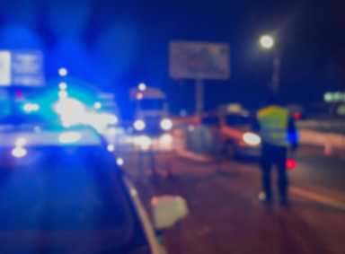 Unrecognizable blurry police car lights and police force officer on night road background, crime scene, night patrolling the city. Abstract  defocused image.