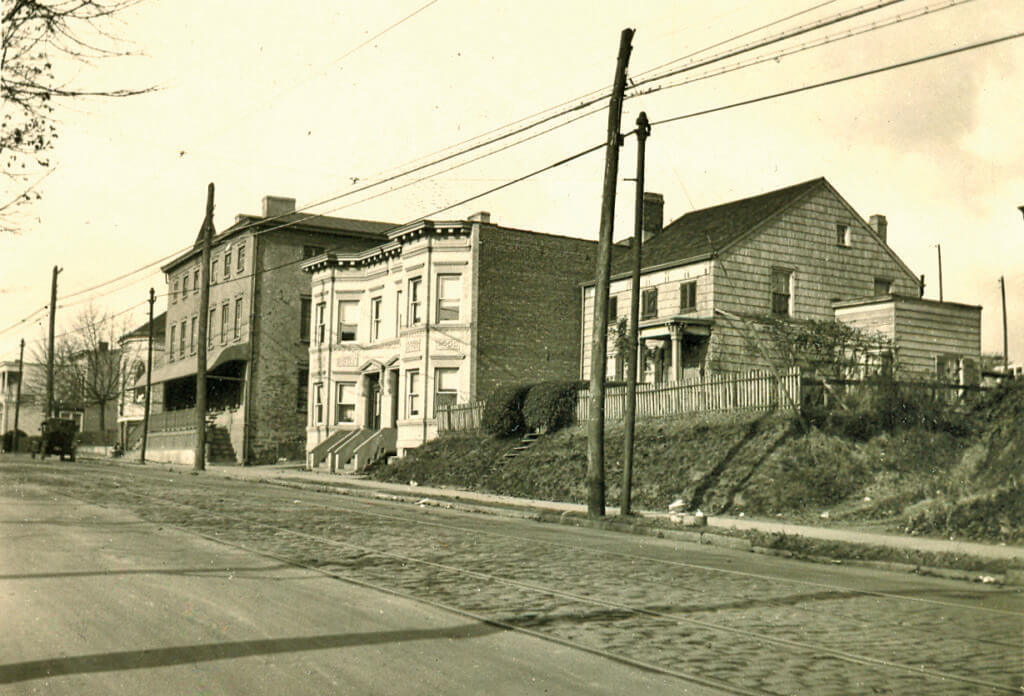 This 1922 photo taken by Eugene Armbruster shows the Metropolitan Avenue streetscape near present-day 78th Street in Middle Village. The three-story former Brick Tavern, built and opened in 1845, is shown in the backgrond at left.
