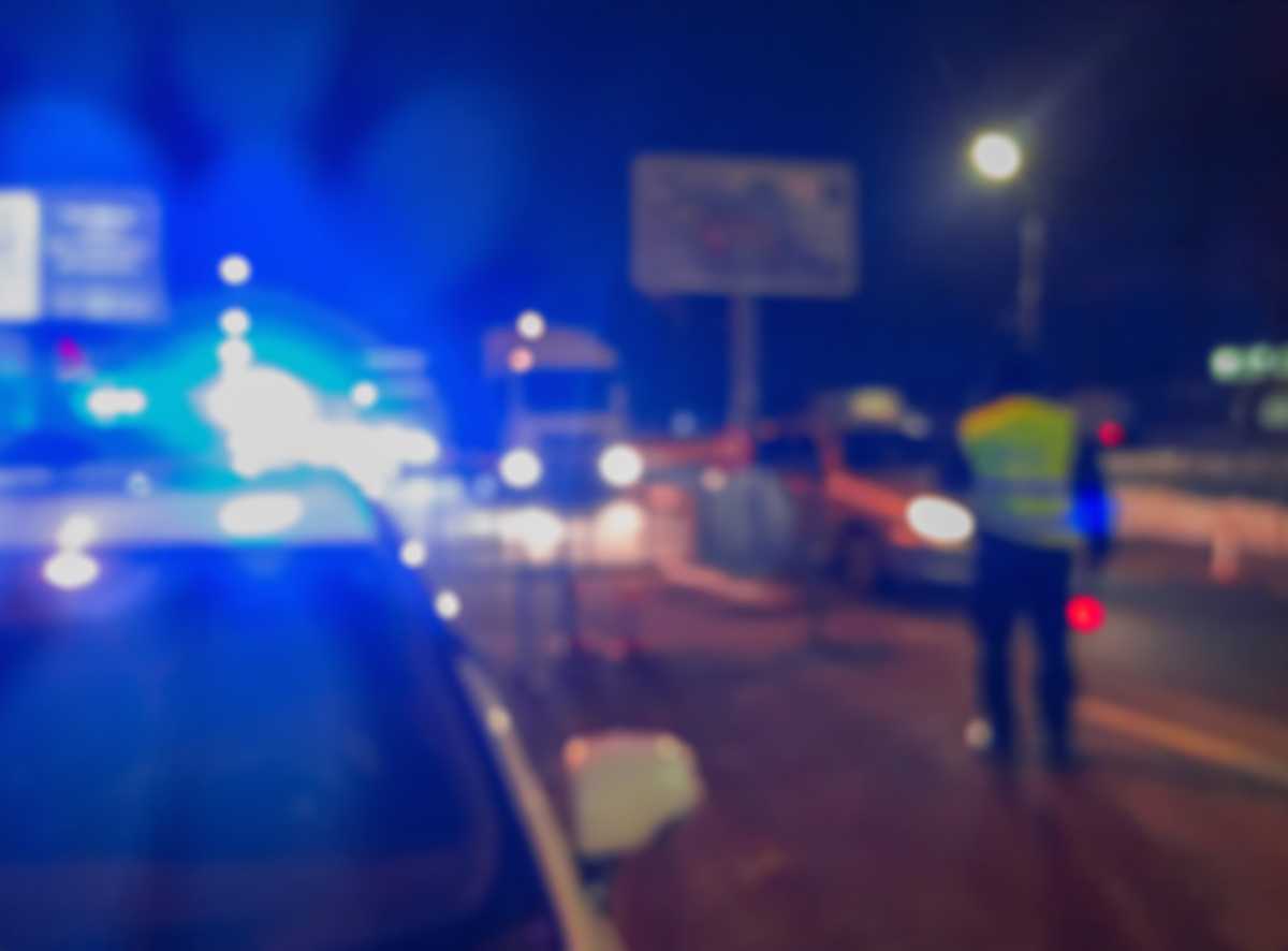 Unrecognizable blurry police car lights and police force officer on night road background, crime scene, night patrolling the city. Abstract  defocused image.