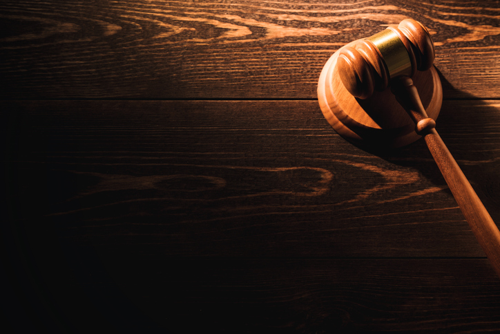 Wooden judge gavel hammer on wooden table background. Dramatic light. Copy space