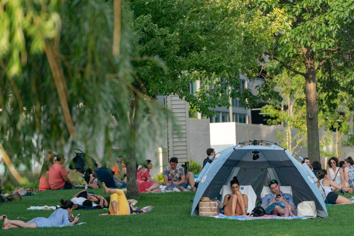 People try to maintain social distance while enjoying a warm and humid day at Gantry Plaza State Park following the outbreak of the coronavirus disease (COVID-19), in Long Island City, New York