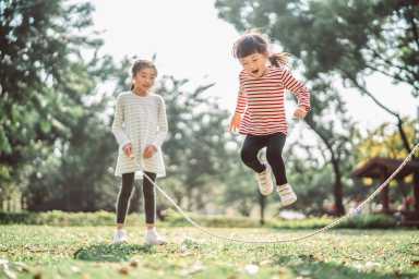 Young family jumping rope joyfully on the lawn