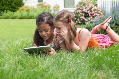 Girls using digital tablet in grass