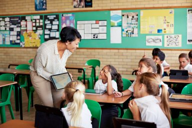 Teacher interacting with kids in class with tablet