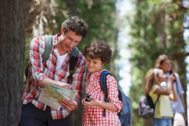 Father and son looking at map in woods