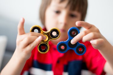 Little child, boy, playing with two fidget spinner toys