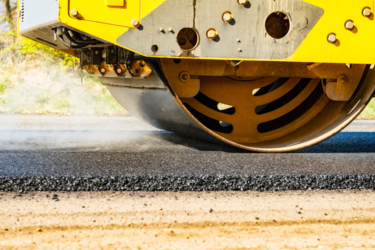 Close-up of an asphalt compacting roller working on highway asphalt resurfacing project