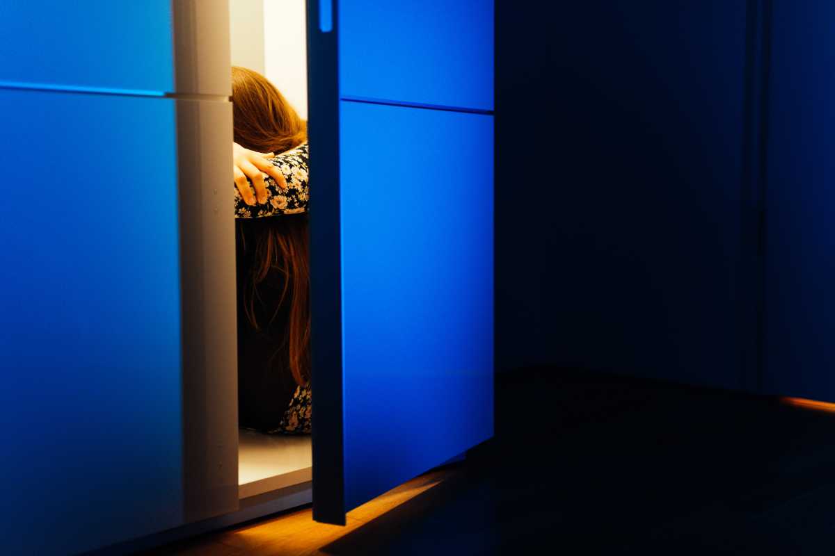 Sad woman sitting in cabinet in the dark.