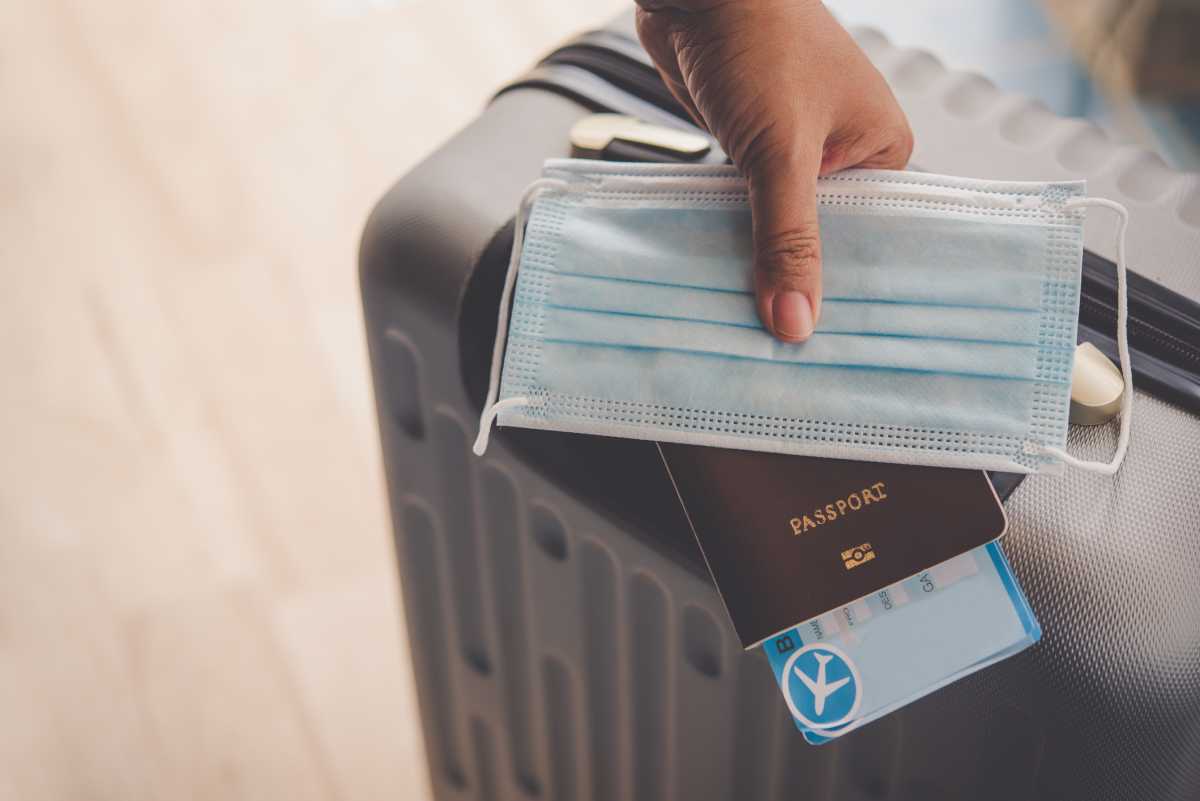 hand holding passport and mask with luggage, concept tourism planning and new normal travel