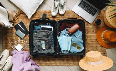 Packing suitcase for travel vacation in new normal, top view.