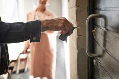 Close-up of mature couple opening door to holiday rental apartment with key