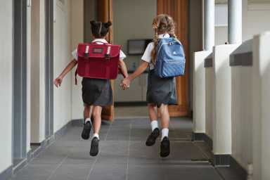Schoolgirls running hand in hand on the isle of school and laughing