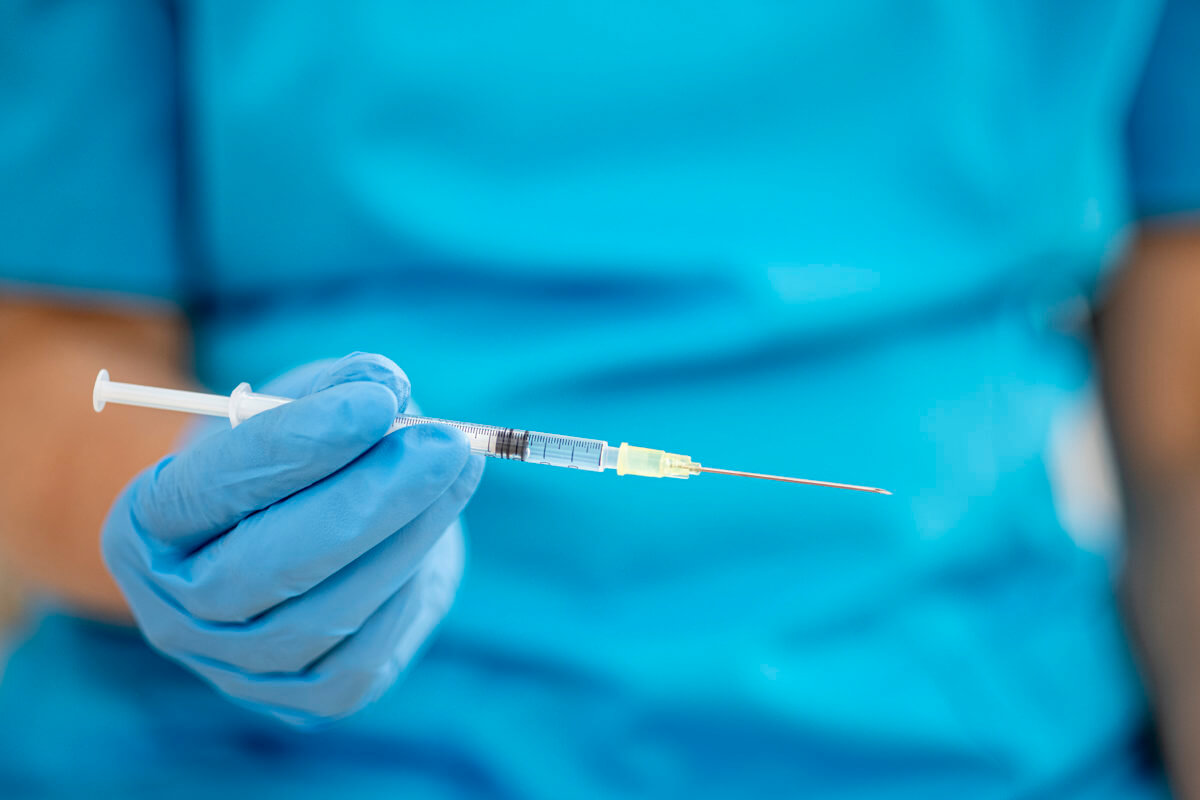 gloved hand holding a syringe for vaccination