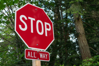 Stop -all way – sign – on a wooden pole with trees in the background