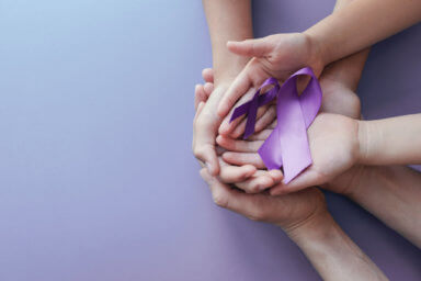 Adult and child hands holding purple ribbons, Alzheimer’s disease, Pancreatic cancer, Epilepsy awareness, world cancer day on purple background