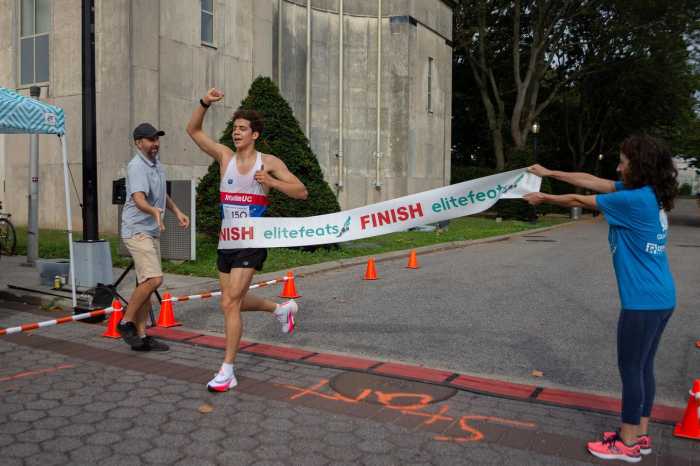 A runner crossing the finish line at the Global Kids 5K walk/run event held at Flushing Meadows Corona Park