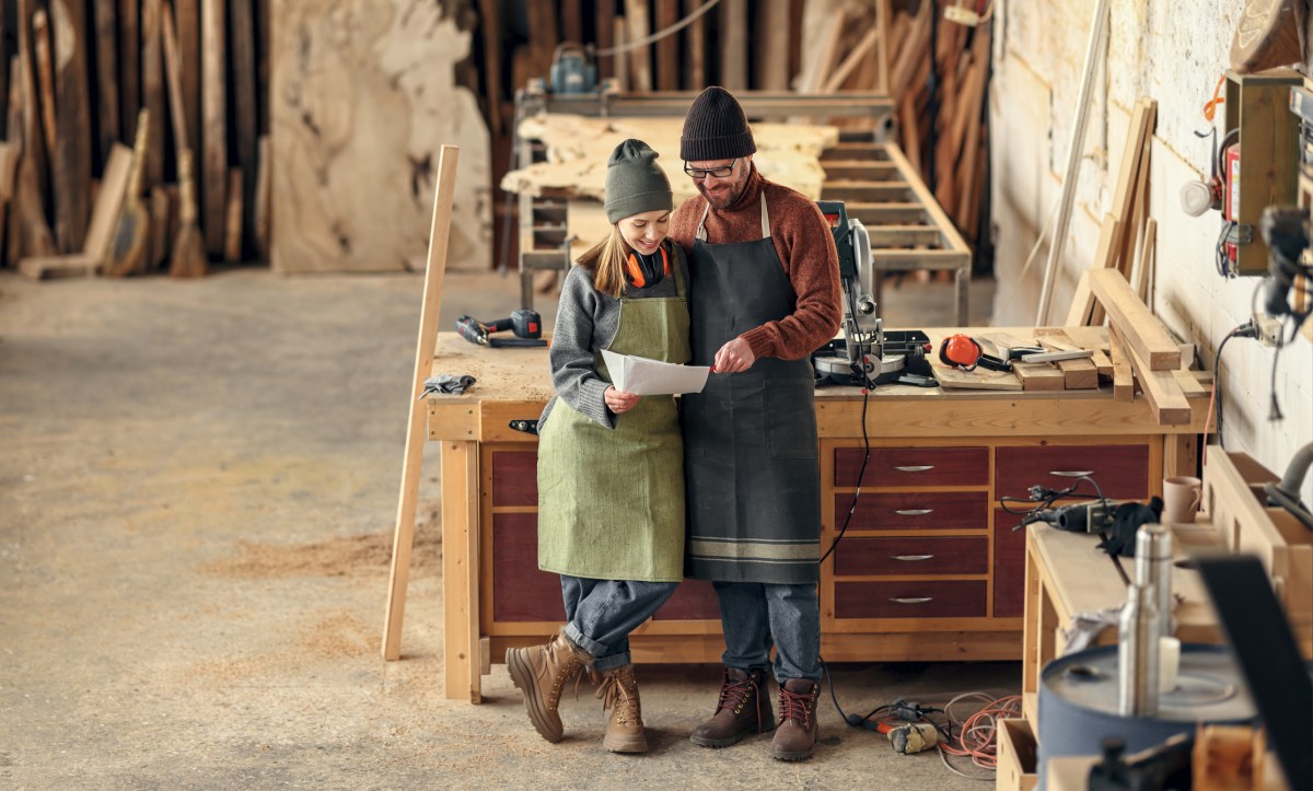 Couple of woodworkers discussing papers in workshop