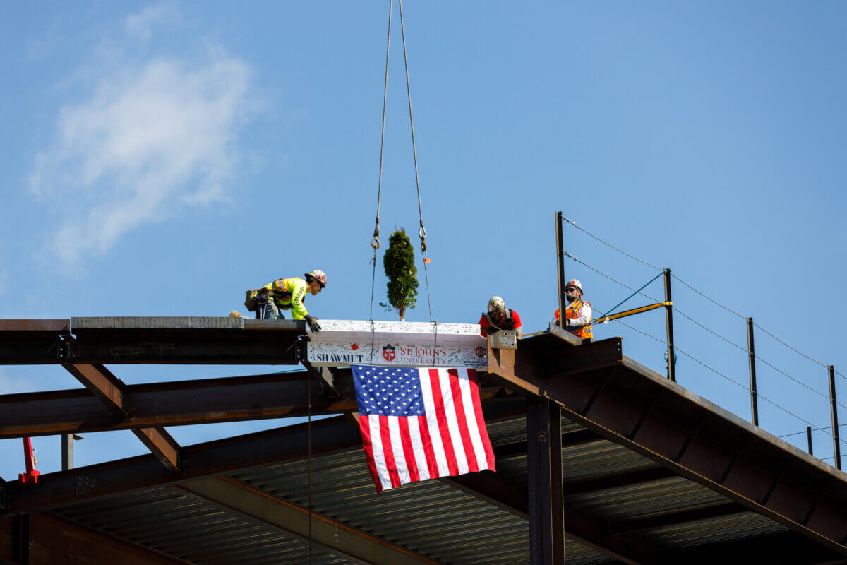 Ironworkers place the final beam during a topping off ceremony for St. John’s University’s St. Vincent Health Sciences Center on Tuesday, April 25. 2023.