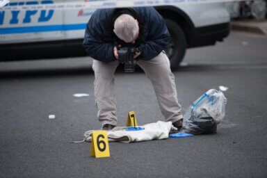 A Crime Scene Techican takes photos at the scene of a triple stabbing.