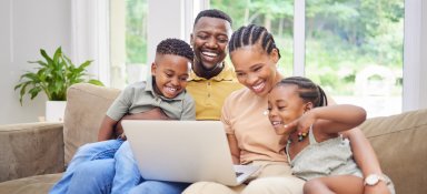 Shot of a young family sitting on the sofa together at home and using a laptop