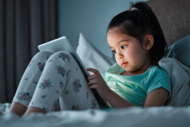 Shot of a little girl using a digital tablet while lying on her bed
