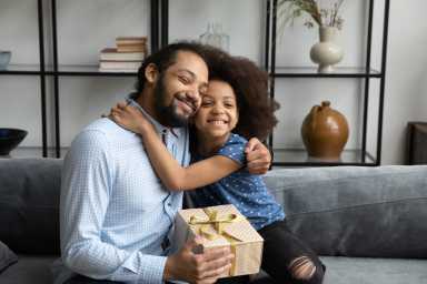 Cheerful daughter kid embracing grateful thankful dad holding surprise gift