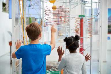 Two kids looking at a science exhibit,  back view