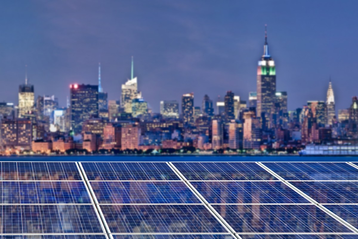 Blue solar cell panels, New York skyline illuminated at night in the background