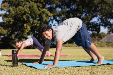 Portrait of happy boy practicing yoga with friend at park