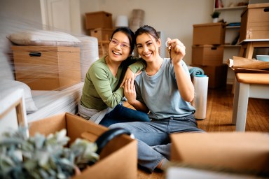 Happy female couple holding a key while after moving into their new apartment.
