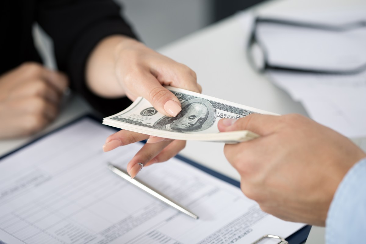 Woman taking batch of hundred dollar bills