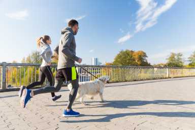 happy couple with dog running outdoors