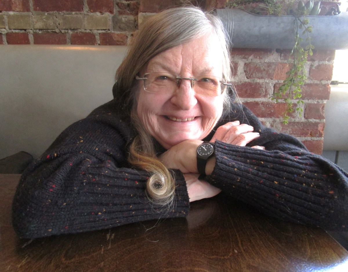 A senior woman smiling in the camera with glasses.