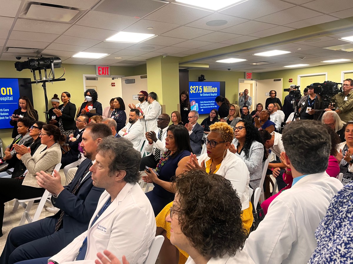 doctors and nurses sitting in a packed room clapping.