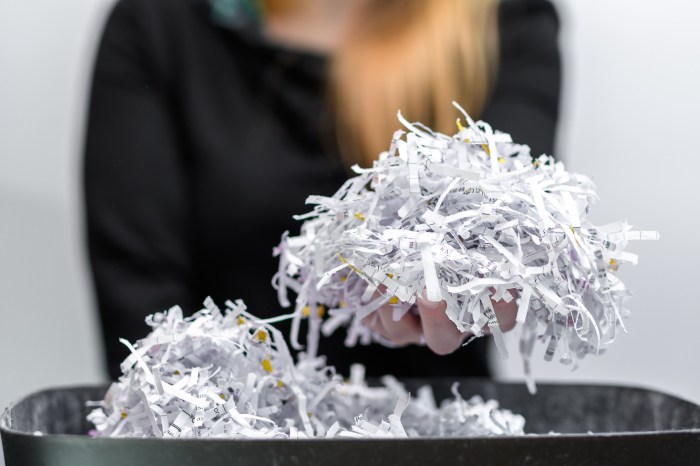 The woman holds waste paper, damaged, torn office documents in her hand