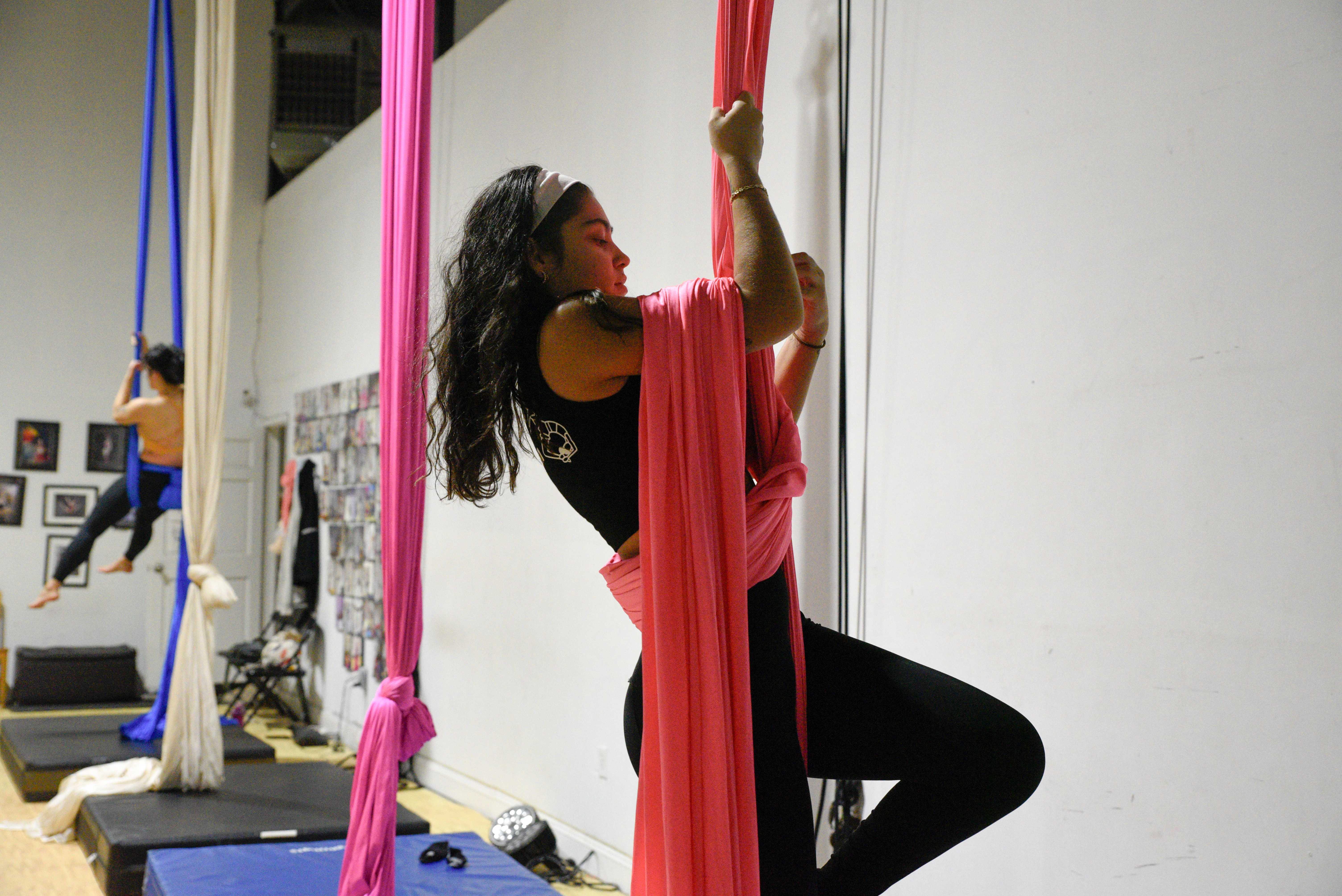 An advanced aerial student climbs a silk