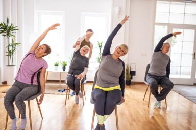 Active senior people practicing yoga during yoga class on chairs