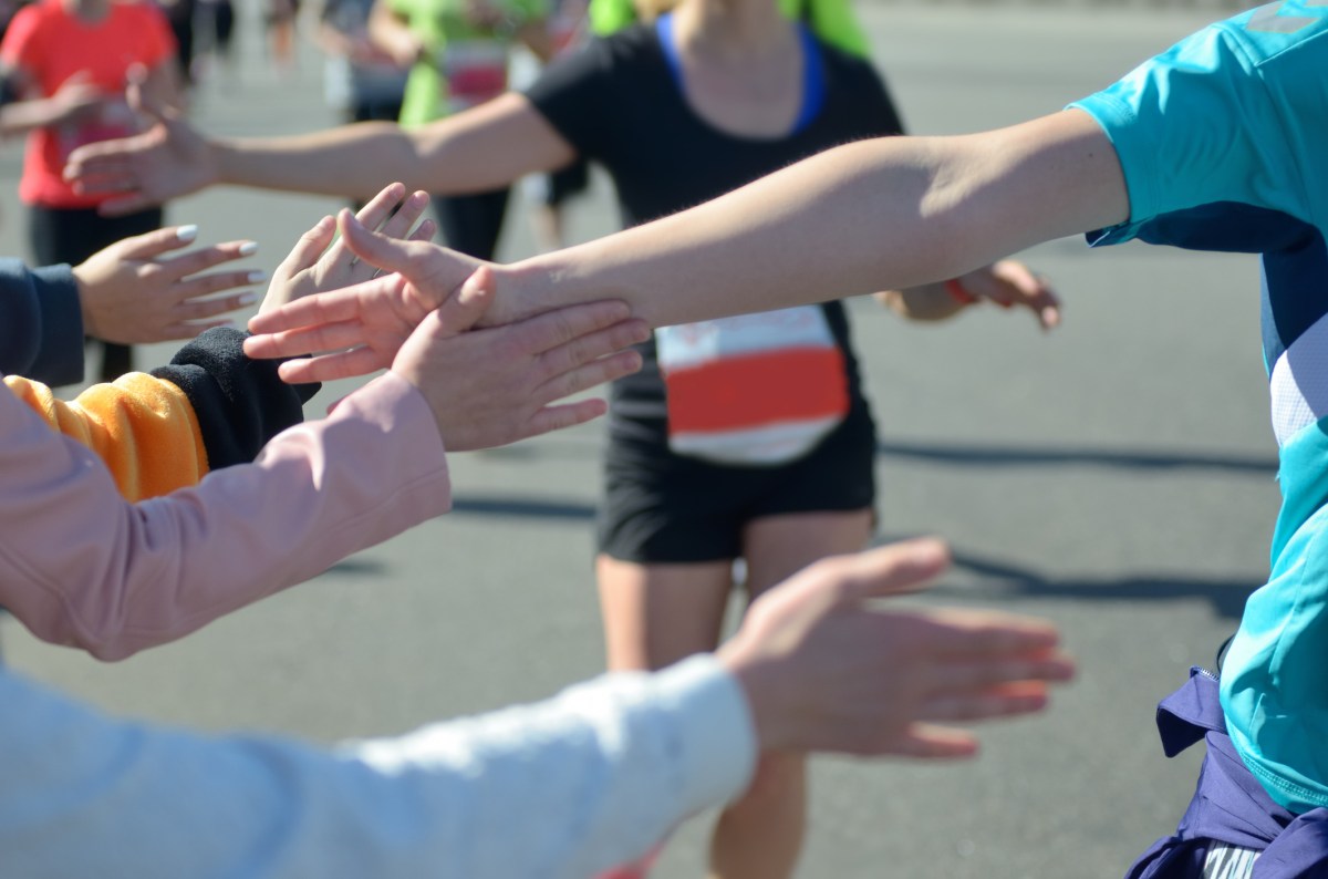 Marathon running race, support runners on road, child’s hand giving highfive, sport concept