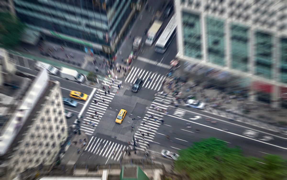 New York city street full of taxis, cars and pedestrians. Yellow cab in focus. Busy NYC Downtown. Crowd of people crossing crosswalks. Traffic jam in NY.