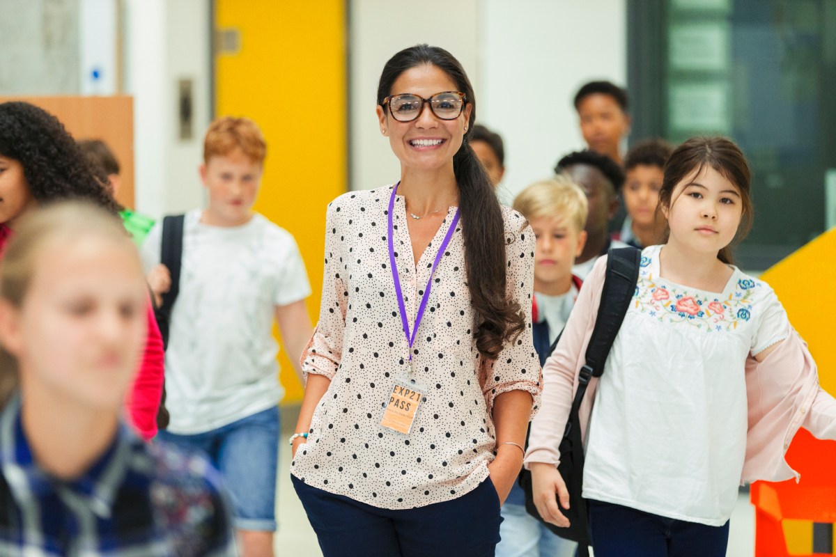 Junior high students walking around smiling female teacher