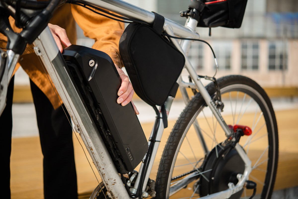 Unrecognizable woman changing battery on her electric bicycle