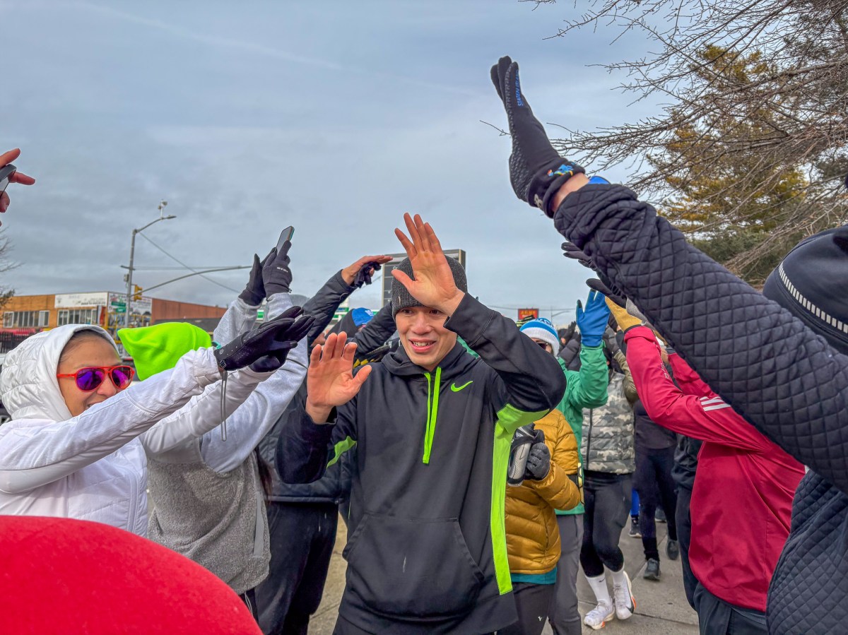 A crowd of runners welcoming runners down the sidewalk at Flushing.