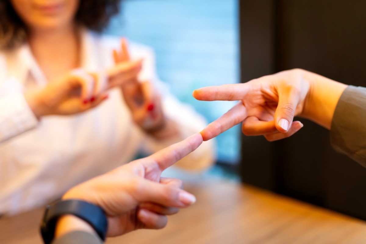 Two young woman communicate with sign language