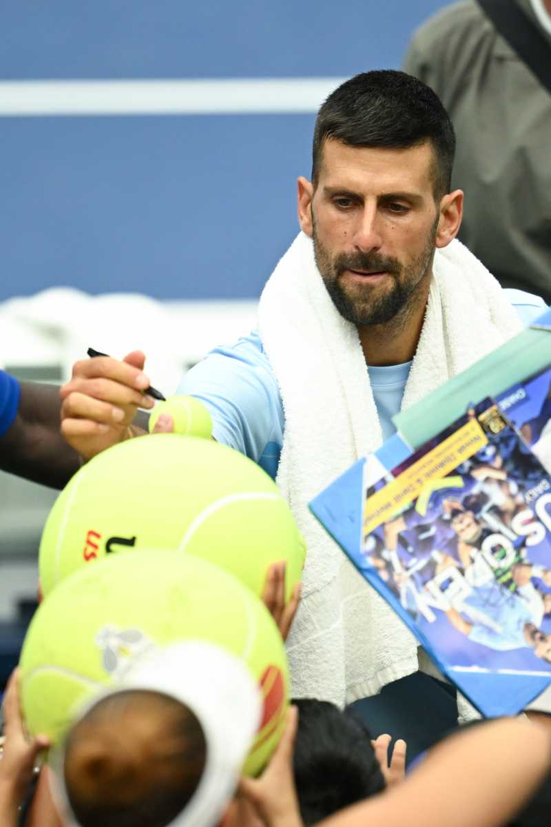 Novak Djokovic autographs a ball during practice at the 2024 US Open.