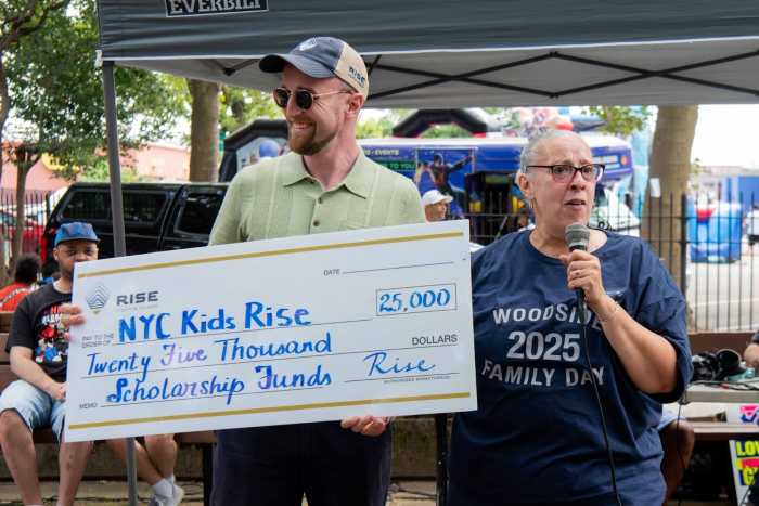 Rise Light & Power Director of External Affairs Wil Fisher announcing a $25,000 investment in students’ college and career futures through the Rise Light & Power Community Scholarship 2025 with Woodside Houses Resident Association President Tammy Reyes. The money goes towards the NYC Scholarship Accounts of rising fifth grade students in the Save for College Program who live in Queensbridge, Ravenswood, Astoria and Woodside Houses (July 19, 2025). Photo by Bridget Ye for NYC Kids RISE.